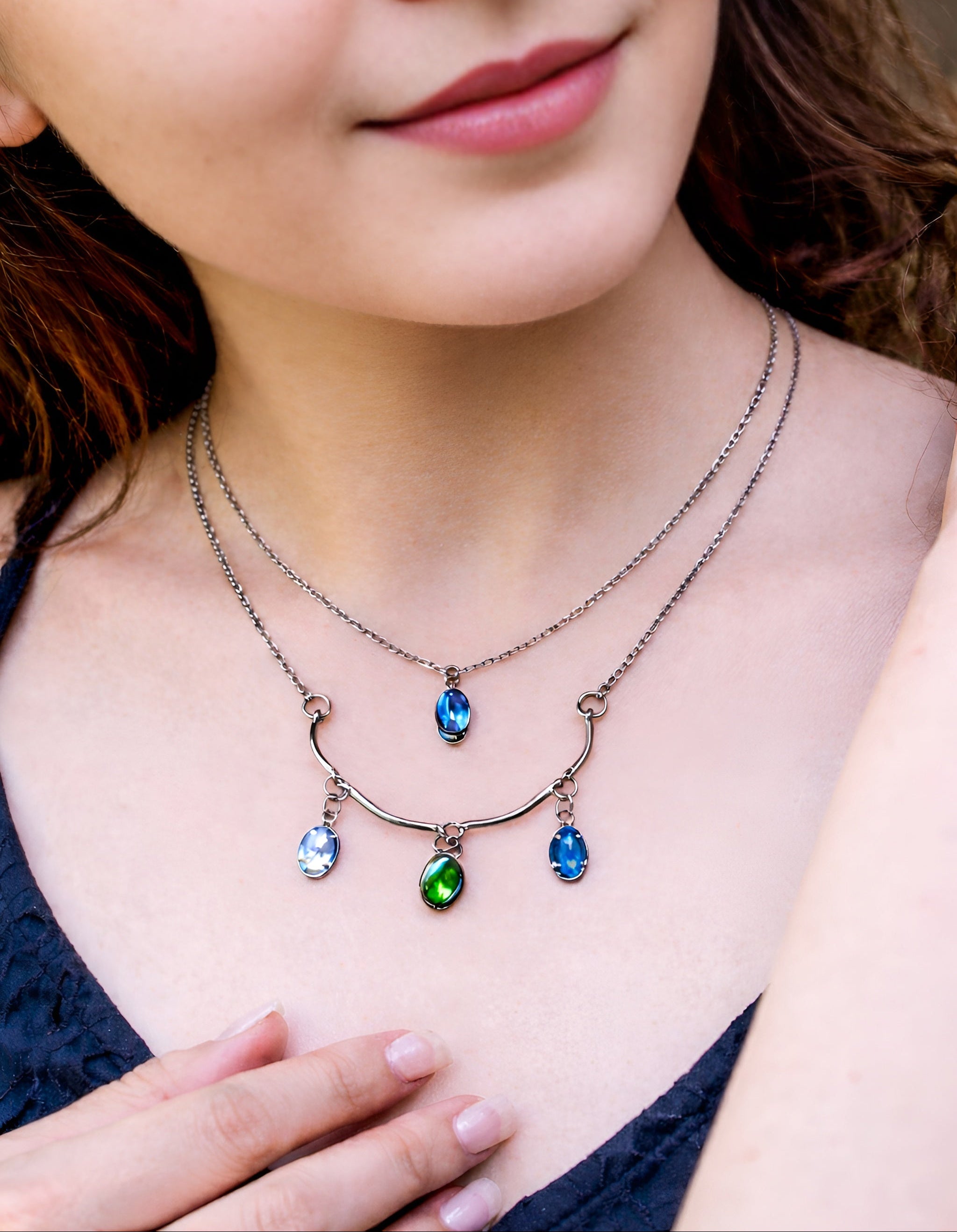 Close-up of a woman wearing a necklace with colorful pendant drops.